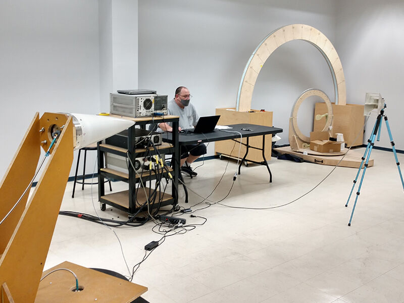 Image of RWC's in-house RF testing area. There is a technician sitting at a computer and a CMC high-speed radome on a testing platform. The radome is undergoing scatter testing.